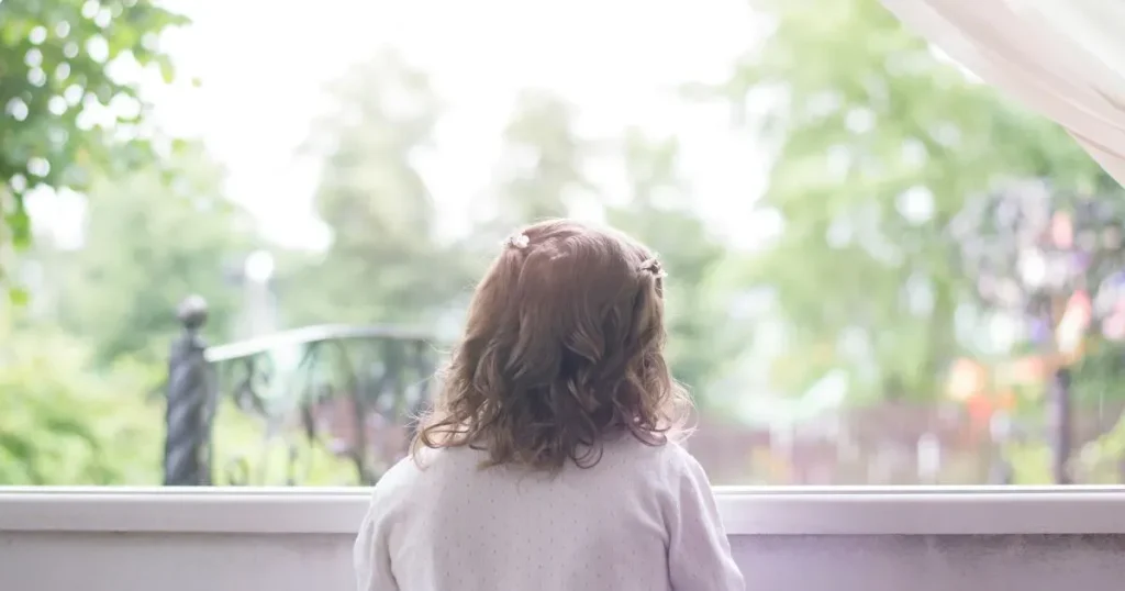 窓の外を見る子どもの後ろ姿