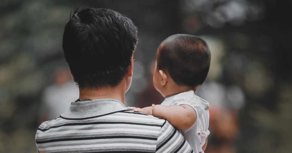 子どもを抱いた親の後ろ姿