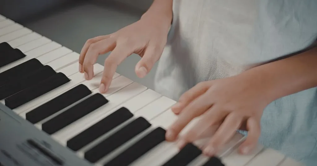 ピアノの鍵盤に置かれた子どもの手元
