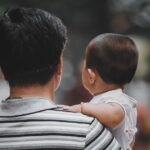 子どもを抱いた親の後ろ姿