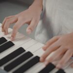 ピアノの鍵盤に置かれた子どもの手元